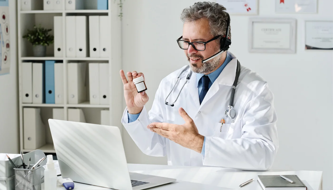 Doctor on video call holding medicine bottle.